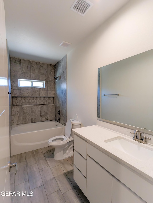 full bathroom with vanity, tiled shower / bath combo, and toilet