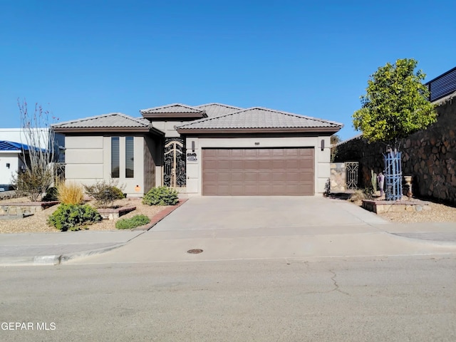 prairie-style house with a garage, stucco siding, driveway, and a tile roof