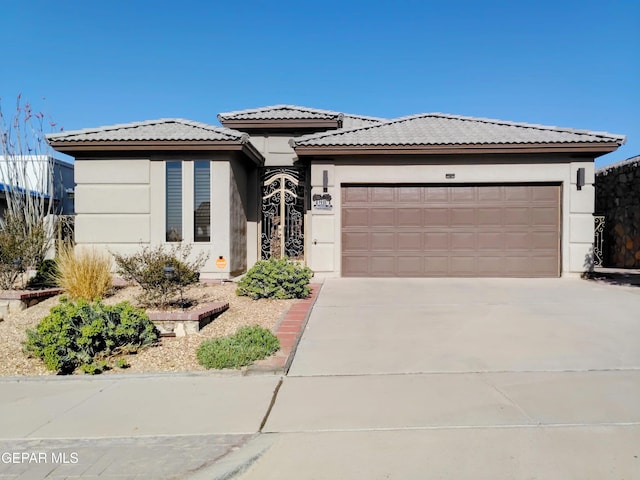 prairie-style home featuring driveway, stucco siding, an attached garage, and a tile roof