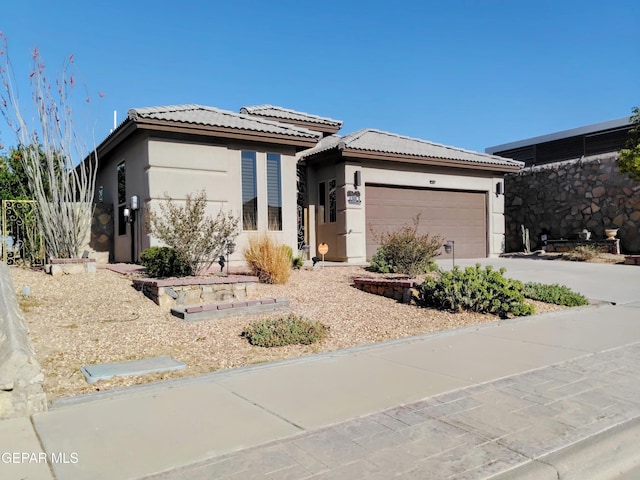 prairie-style house featuring a tiled roof, a garage, stucco siding, and driveway