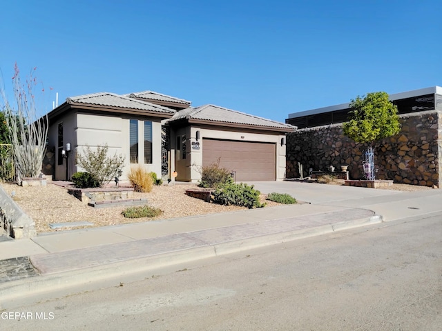 prairie-style house with a garage, stucco siding, concrete driveway, and a tile roof