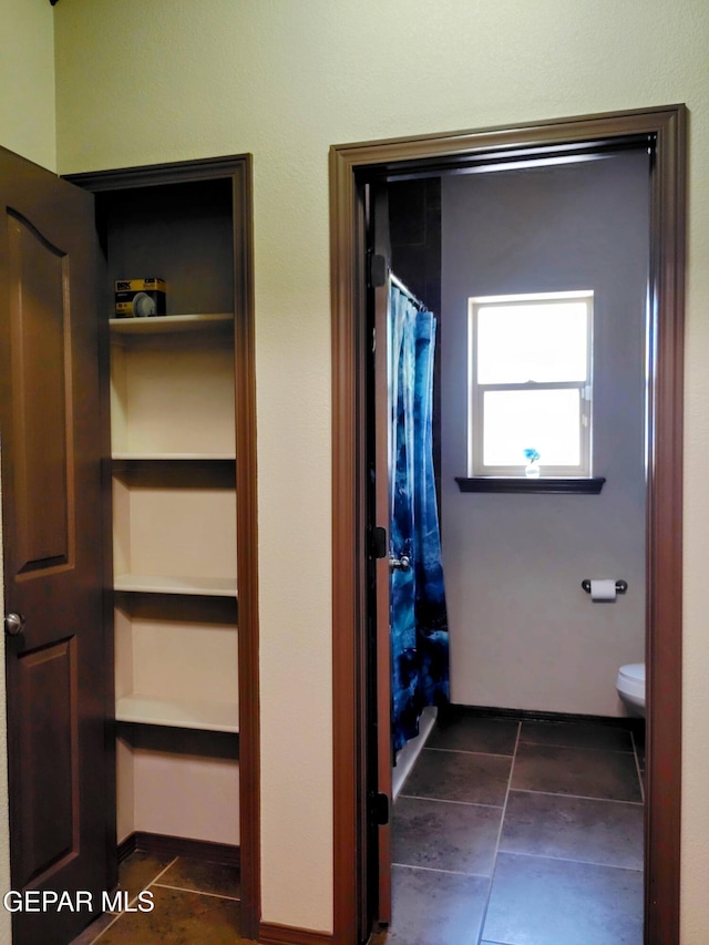 bathroom with toilet, a shower with shower curtain, and tile patterned flooring