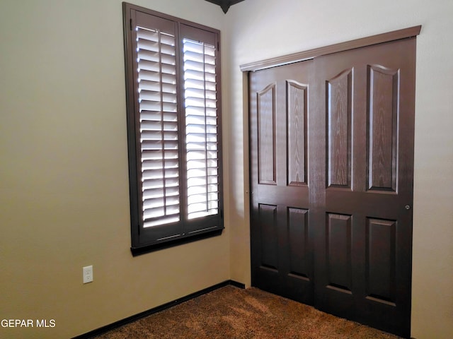 interior space featuring dark carpet and baseboards