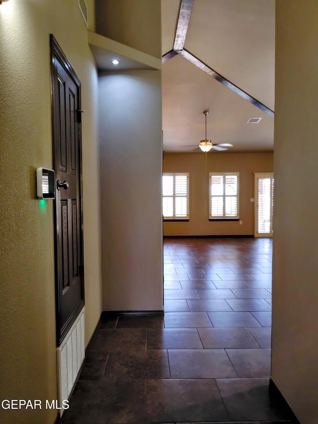 foyer featuring a textured wall, visible vents, baseboards, and ceiling fan