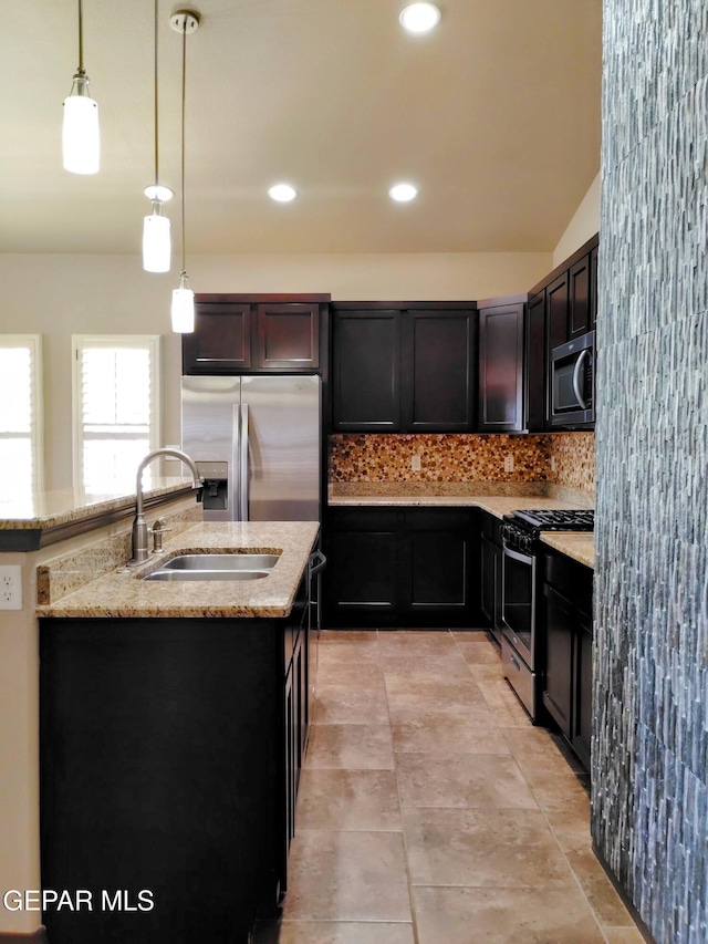 kitchen featuring tasteful backsplash, a sink, appliances with stainless steel finishes, light stone countertops, and pendant lighting