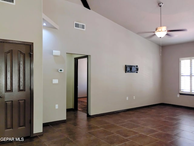 empty room with visible vents, baseboards, ceiling fan, and a high ceiling