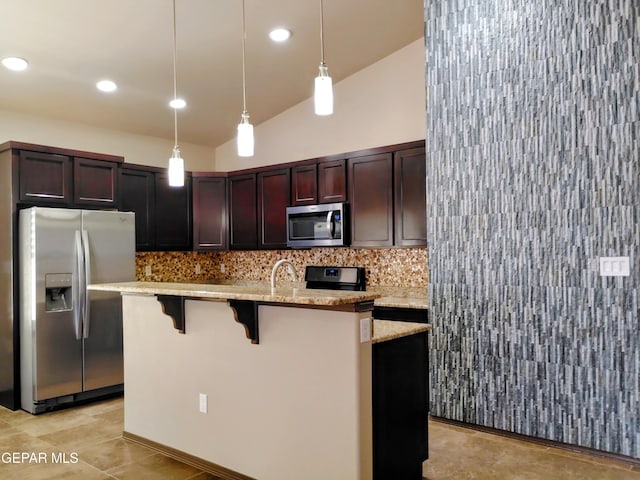 kitchen with an island with sink, hanging light fixtures, decorative backsplash, and appliances with stainless steel finishes