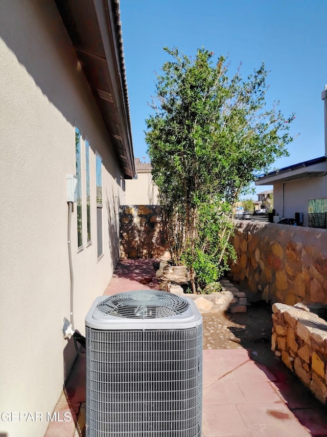 details featuring fence, cooling unit, and stucco siding