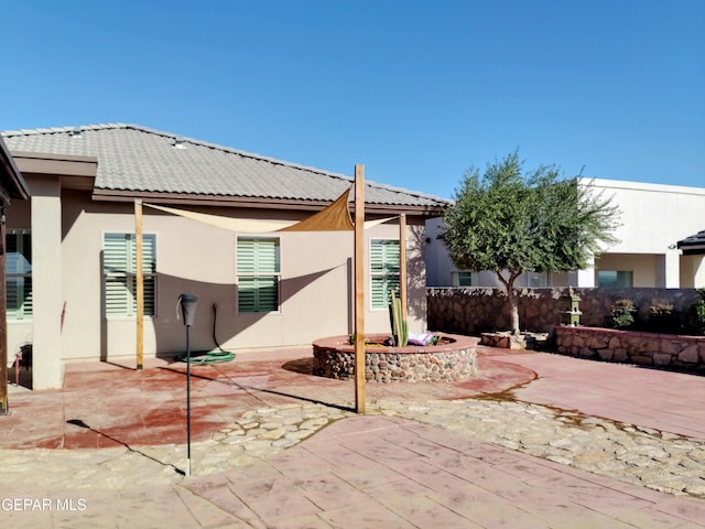 rear view of house with a patio, stucco siding, fence, and a tile roof