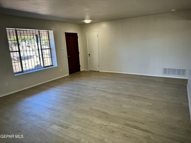 empty room featuring a textured ceiling and light wood-type flooring