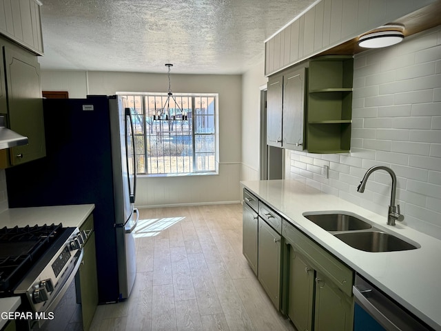 kitchen with tasteful backsplash, sink, green cabinets, stainless steel appliances, and light hardwood / wood-style flooring