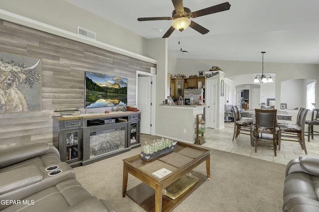 living room with lofted ceiling, ceiling fan with notable chandelier, light carpet, and wood walls