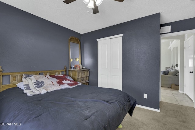 bedroom with ceiling fan, light colored carpet, a closet, and a textured ceiling