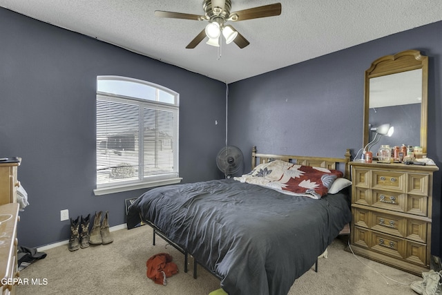 bedroom with multiple windows, light carpet, a textured ceiling, and ceiling fan