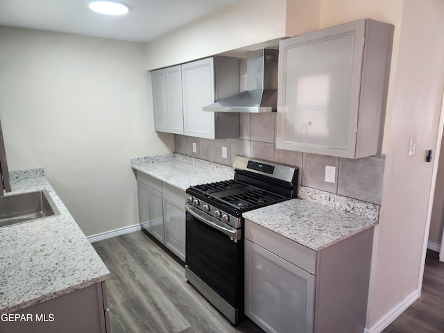 kitchen with gas range, wood-type flooring, wall chimney exhaust hood, and gray cabinets