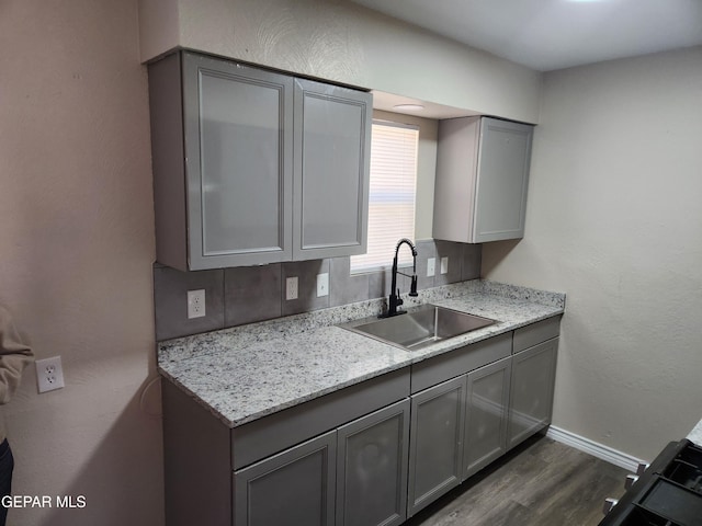 kitchen with tasteful backsplash, sink, gray cabinetry, and dark wood-type flooring