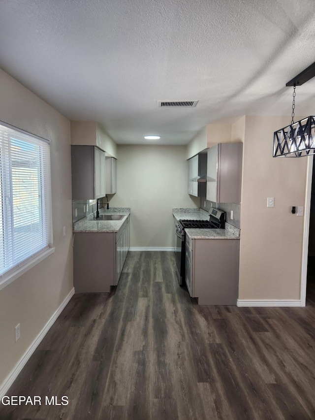 kitchen with decorative light fixtures, sink, gas stove, dark wood-type flooring, and a textured ceiling