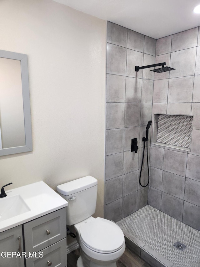 bathroom with vanity, hardwood / wood-style floors, toilet, and tiled shower