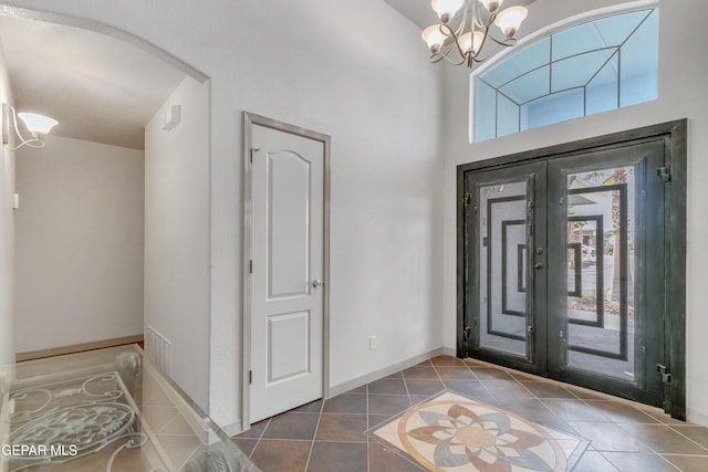 foyer entrance featuring dark tile patterned floors, french doors, and an inviting chandelier