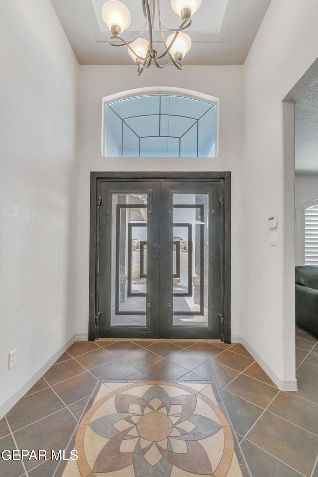 foyer entrance with a chandelier, a high ceiling, a wealth of natural light, and french doors