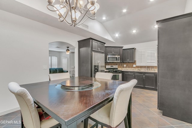 dining area with ceiling fan with notable chandelier, lofted ceiling, and light tile patterned flooring