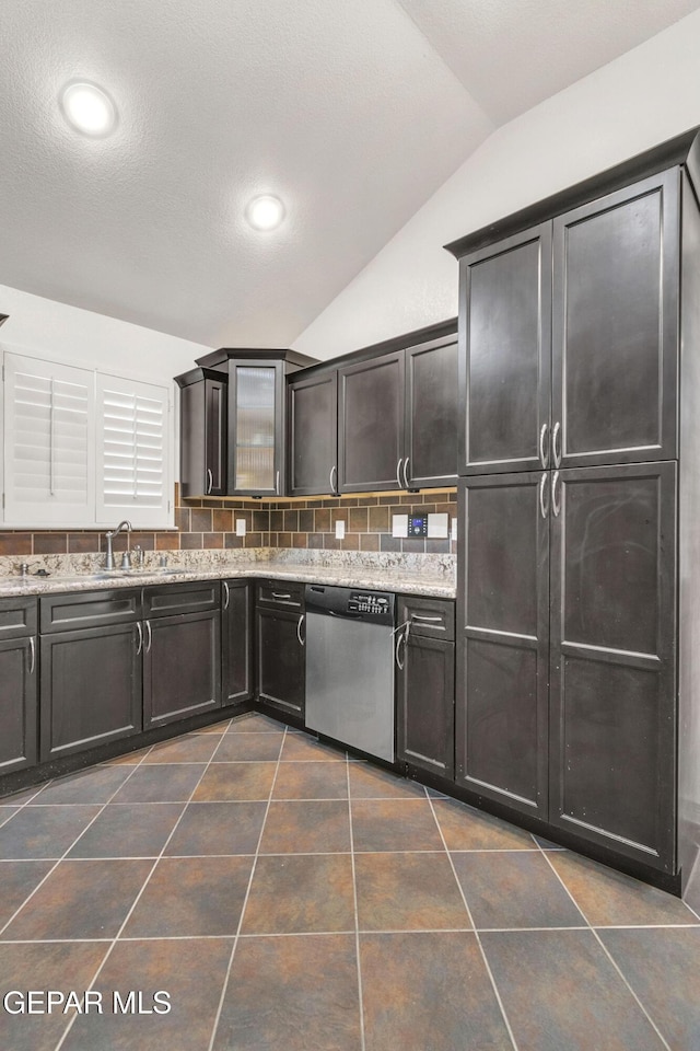 kitchen featuring stainless steel dishwasher, decorative backsplash, lofted ceiling, and light stone counters