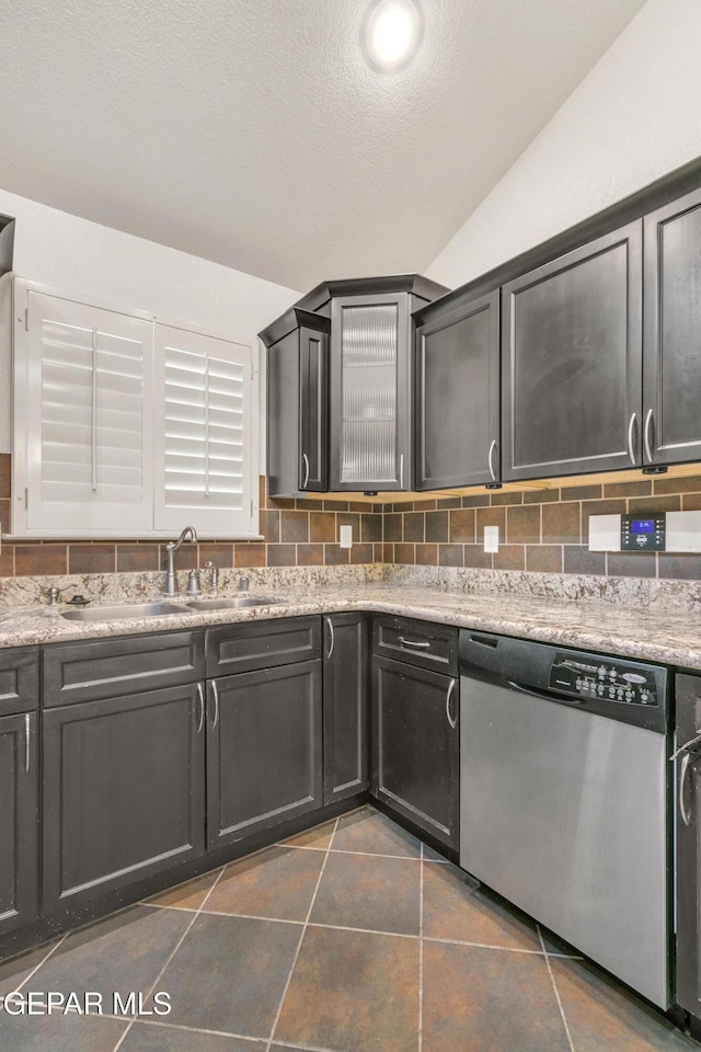 kitchen featuring sink, vaulted ceiling, decorative backsplash, and dishwasher