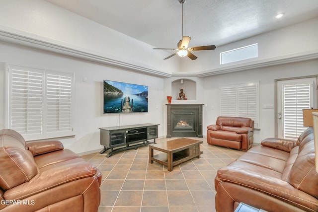 tiled living room with ceiling fan, a textured ceiling, and a towering ceiling