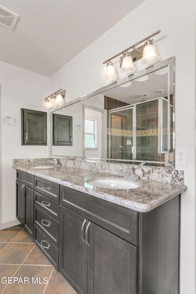 bathroom with a shower with door, vanity, and tile patterned flooring