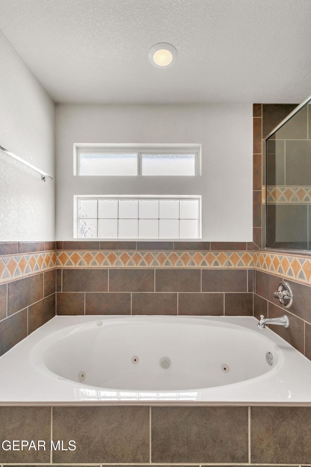 bathroom featuring tiled bath and a textured ceiling