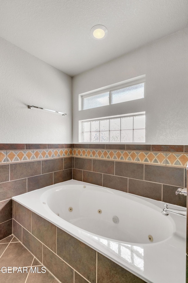 bathroom with tiled bath, a textured ceiling, and tile patterned floors