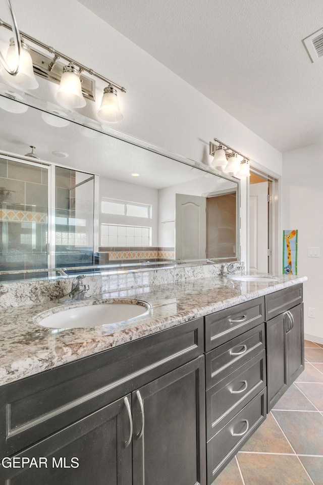 bathroom featuring vanity, a shower with shower door, a textured ceiling, and tile patterned flooring