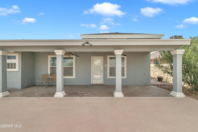 entrance to property with ceiling fan and a patio area