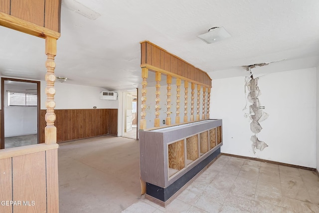 hallway featuring lofted ceiling, a textured ceiling, and wood walls