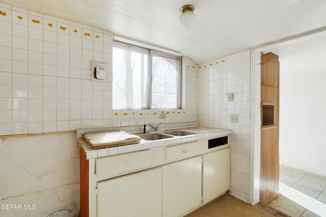 kitchen with sink, tile countertops, tile walls, light tile patterned floors, and decorative backsplash