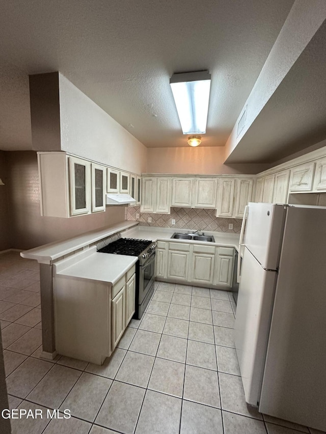 kitchen with white fridge, sink, gas stove, and light tile patterned floors