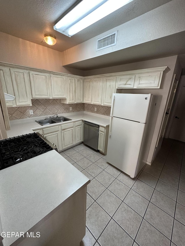 kitchen featuring white fridge, light tile patterned floors, sink, dishwasher, and tasteful backsplash