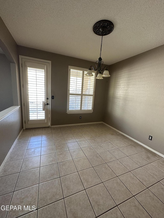 unfurnished dining area with light tile patterned flooring, an inviting chandelier, and a textured ceiling