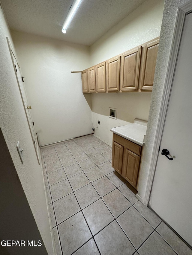 laundry area featuring cabinets, electric dryer hookup, light tile patterned floors, a textured ceiling, and washer hookup