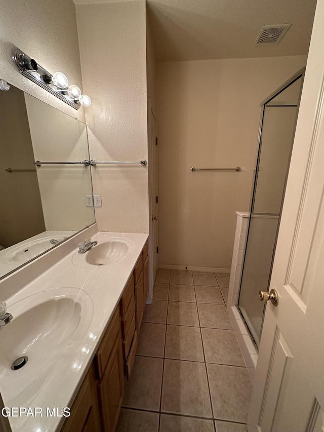 bathroom with a shower with door, tile patterned flooring, and vanity