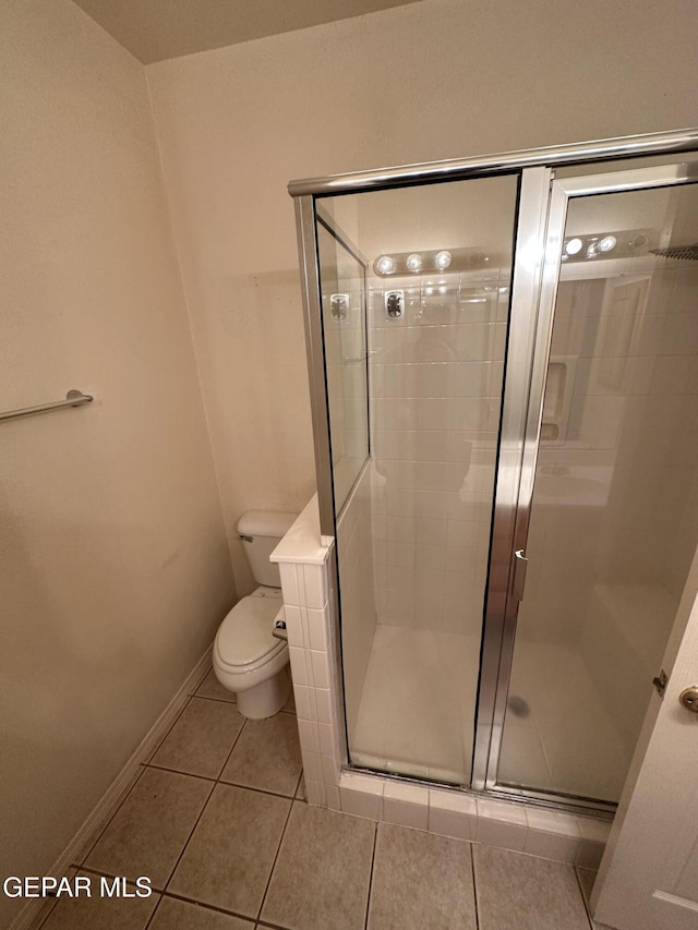 bathroom with tile patterned floors, toilet, and an enclosed shower