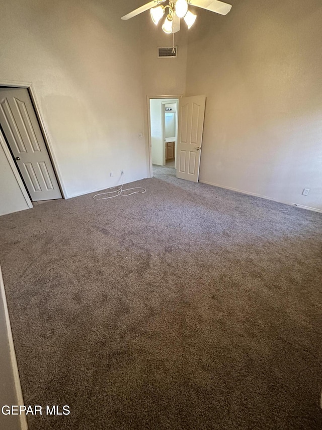 spare room with carpet, ceiling fan, and a high ceiling