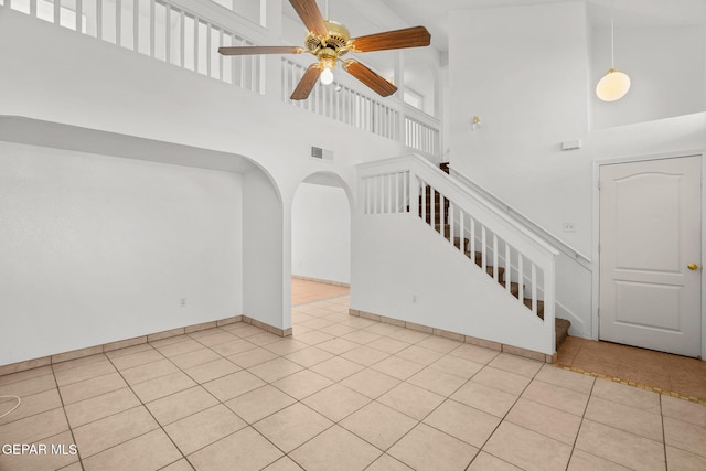 stairway with ceiling fan, a high ceiling, and tile patterned floors