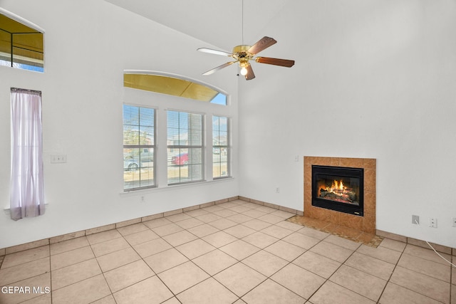 unfurnished living room featuring high vaulted ceiling, ceiling fan, light tile patterned floors, and a tiled fireplace