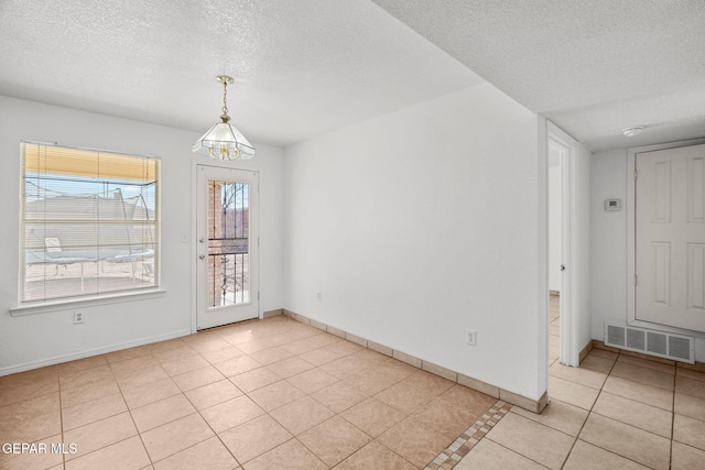 spare room with a textured ceiling and light tile patterned floors