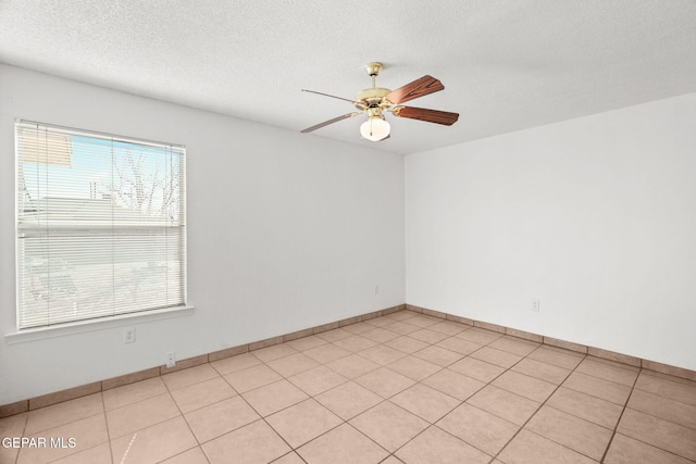 empty room with ceiling fan, a textured ceiling, and light tile patterned floors