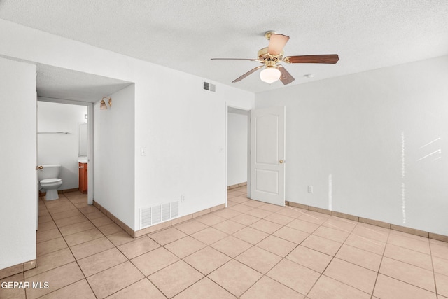 spare room with ceiling fan, a textured ceiling, and light tile patterned flooring