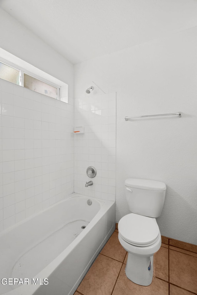 bathroom with toilet, tiled shower / bath combo, and tile patterned flooring