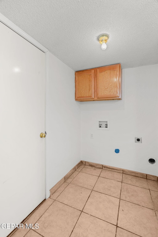 washroom featuring washer hookup, a textured ceiling, light tile patterned floors, and cabinets