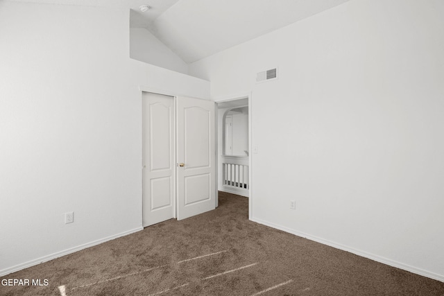 unfurnished bedroom featuring a closet, high vaulted ceiling, and dark carpet